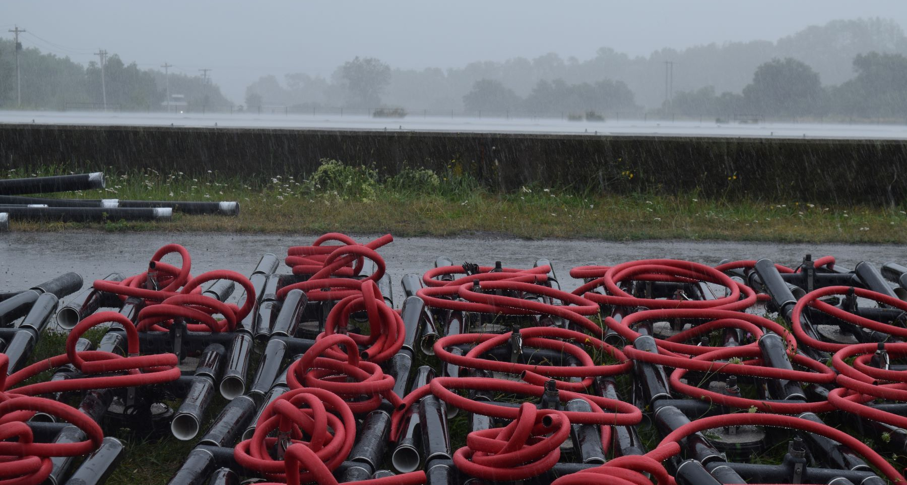 Image showing a sewage treatment lagoon in the Town of Antigonish, Nova Scotia, on a rainy day. In the foreground is new equipment awaiting installation.